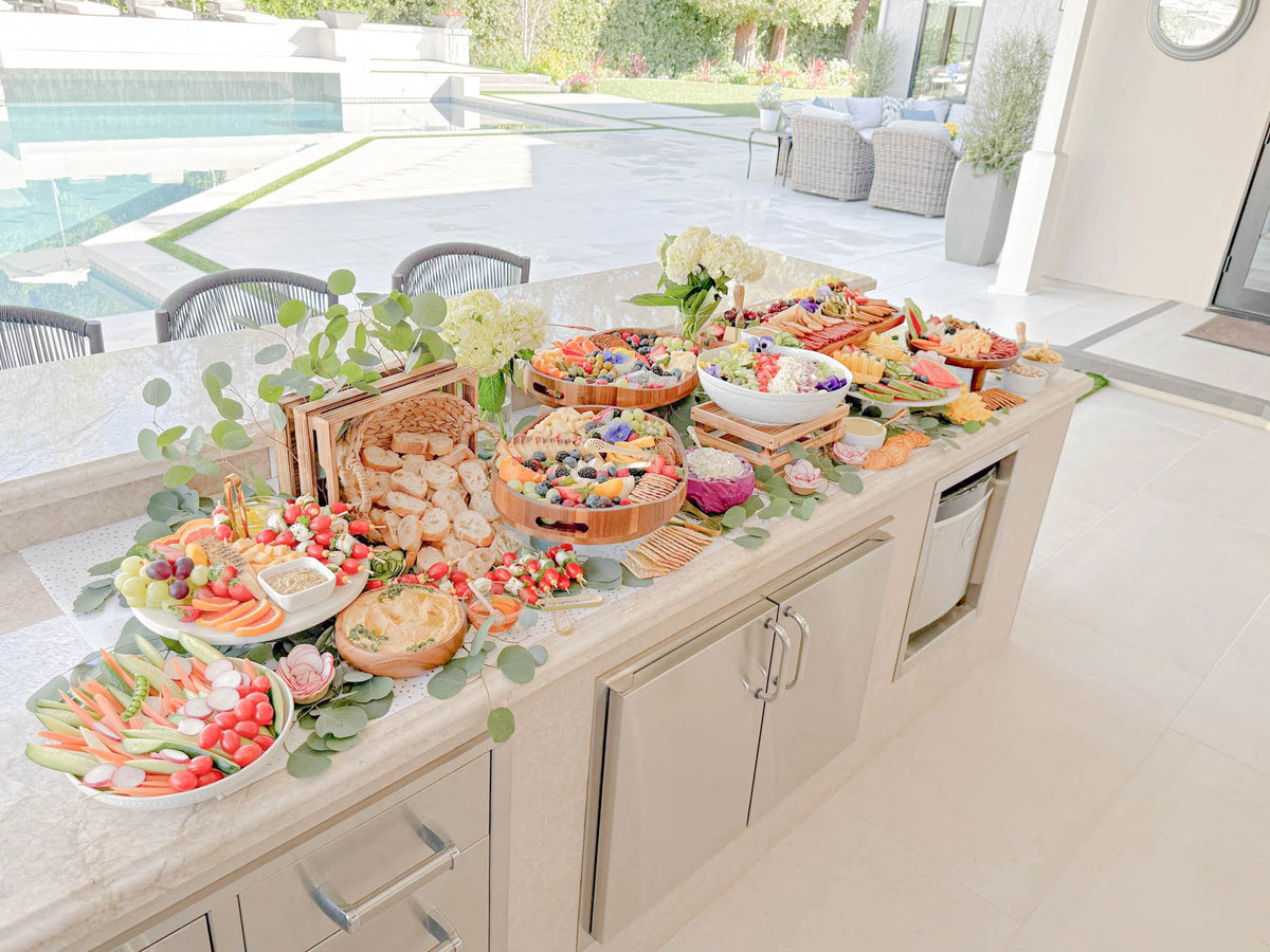 Charcuterie grazing table with artisan cheeses, cured meats, fresh fruit, crackers, and gourmet accompaniments