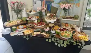 Multi dimensional grazing table by Fork and Flare in Orange County featuring an abundant display of crudités mixed berries grapes kiwi blood oranges caprese skewers olive tapenade hummus spinach and artichoke dip fresh bread mixed nuts and an array of cheeses including goat brie manchego gouda and cheddar perfect for weddings upscale parties and corporate events