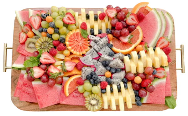 Large fruit platter by Fork and Flare in Orange County, CA, displayed on an acacia wood board with oranges, dragon fruit, grapes, blueberries, gooseberries, kiwi, watermelon, strawberries, pineapple, raspberries, and fresh mint leaves as garnish.